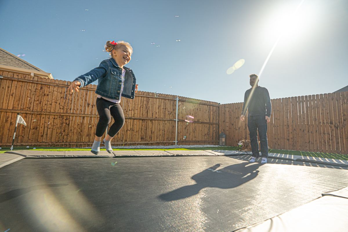 Dad and daughter jumping on an in-ground trampoline