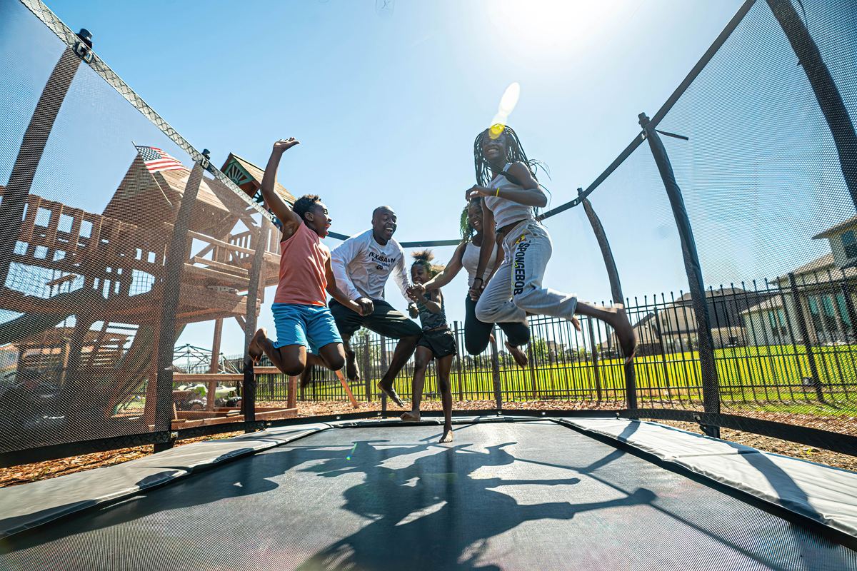 Family jumping together on a rectangle in-ground trampoline