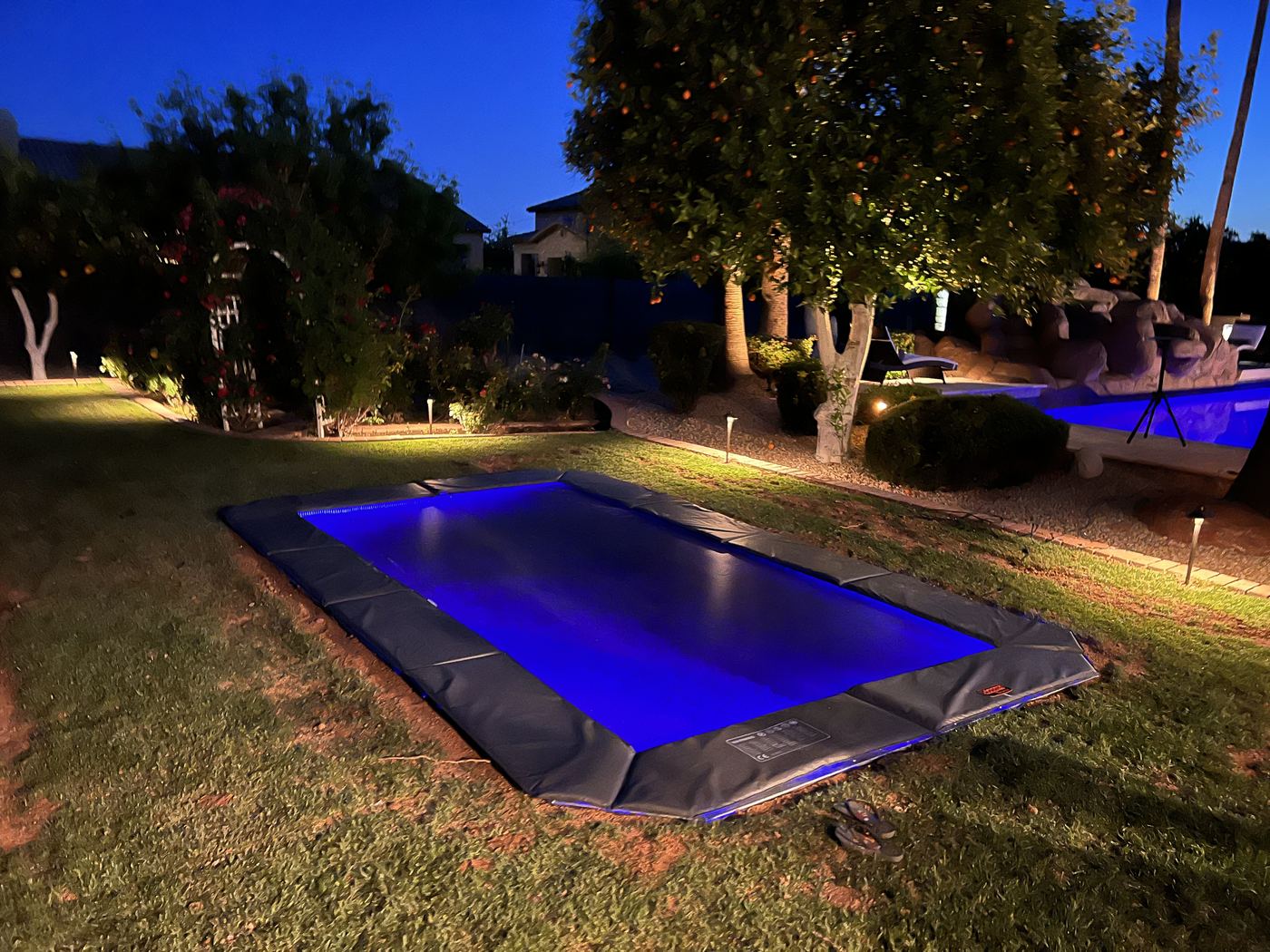 Rectangle in-ground trampoline glowing with blue LED lights at night