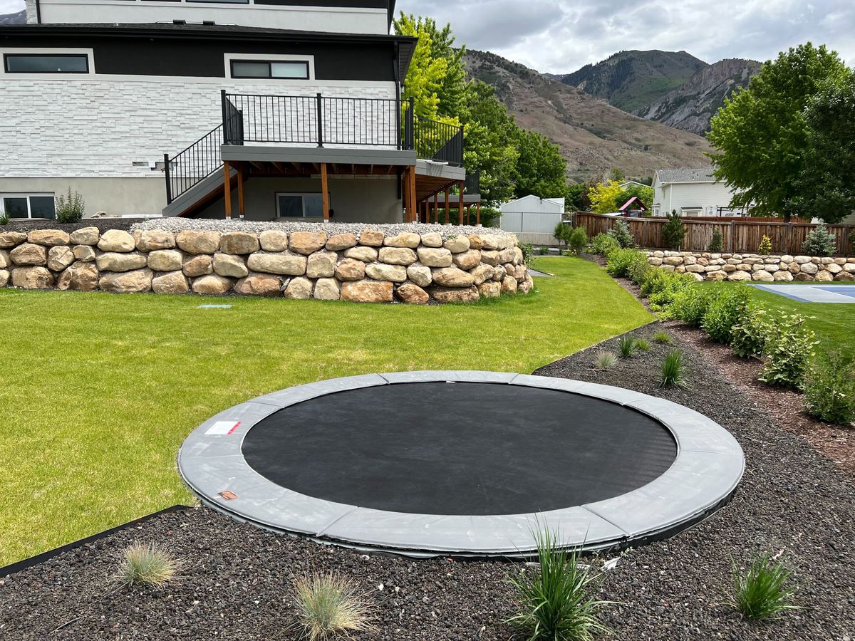 Kids playing on a round in-ground trampoline in Cache Valley