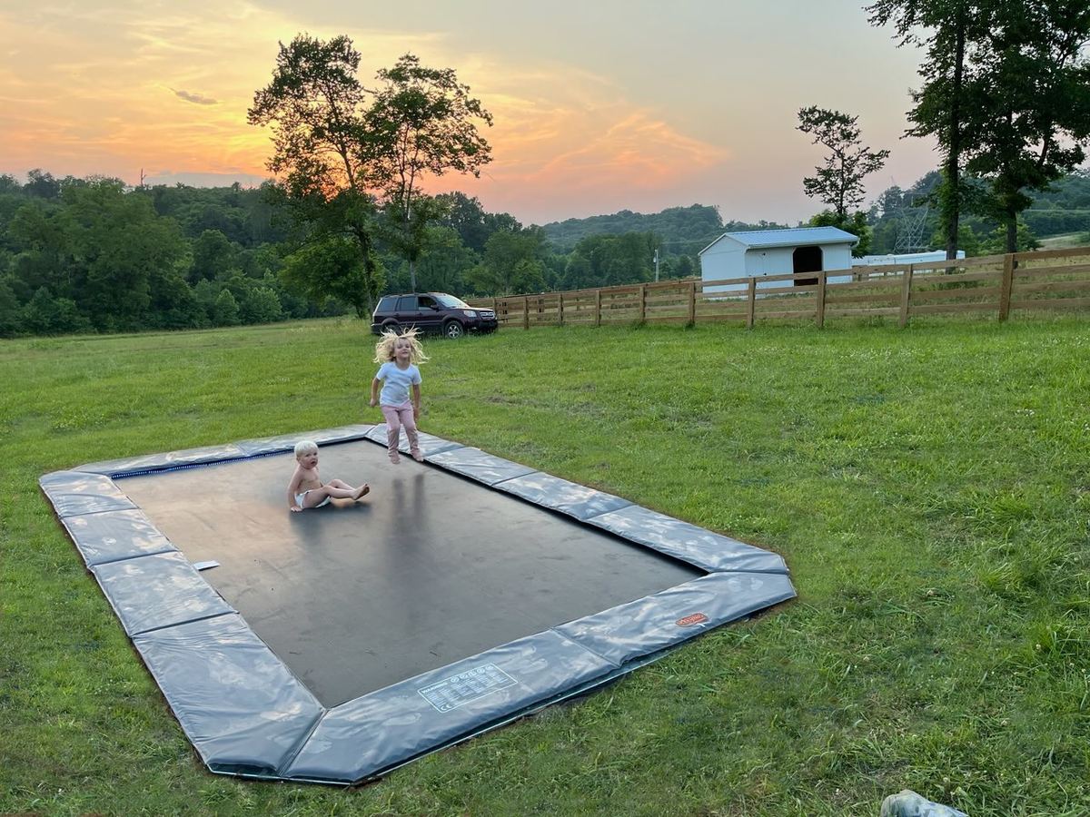 Kids jumping on an in-ground trampoline at sunset